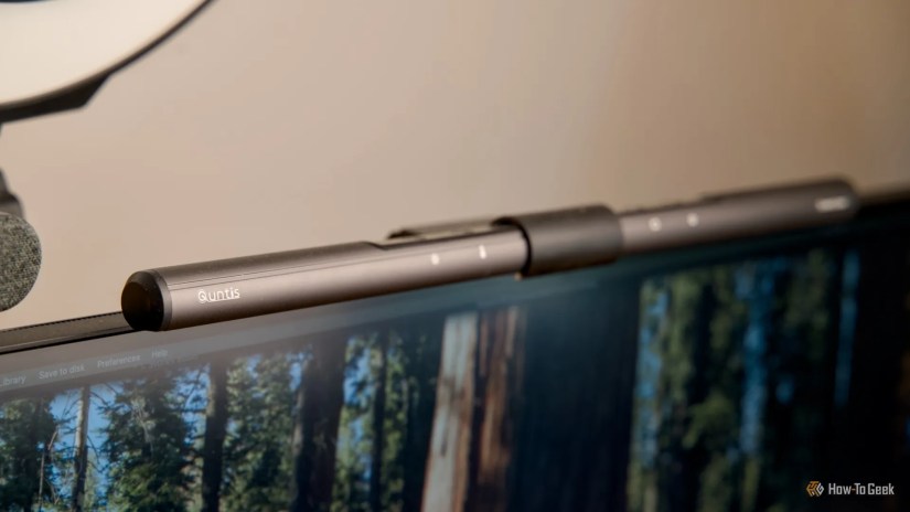 The Quntis ScreenLinear Monitor Light Bar sitting on top of a monitor with a beige wall in the background.