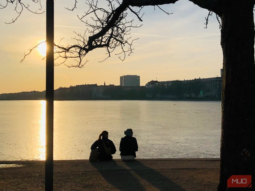 Two people sitting next to a lake with a backlit image