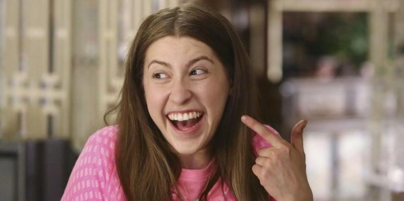 Sue Heck (Eden Sher) from The Middle pointing her finger toward her face and smiling.