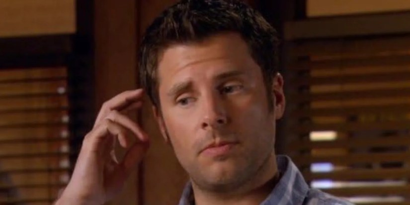 Shawn Spencer is holding his hand up to his face.