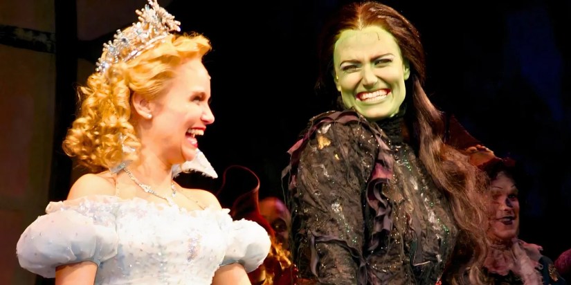 Kristin Chenoweth as Glinda and Idina Menzel as Elphaba laughing and smiling in Wicked