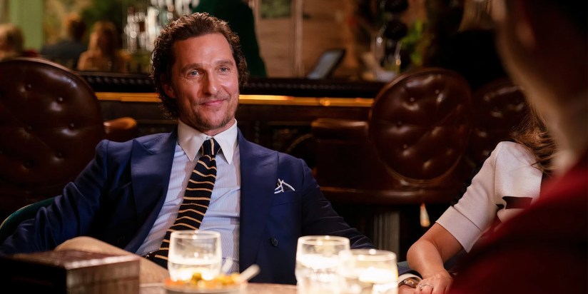 Matthew McConaughey’s Michael Pearson smiling while sitting at a table in The Gentlemen