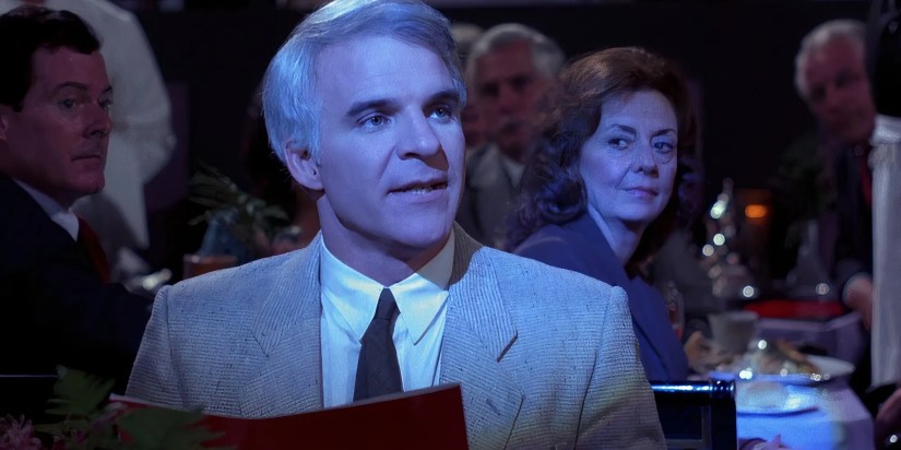 Steve Martin as Larry Hubbard sat in a dark restaurant being watched by other patrons in The Lonely Guy.