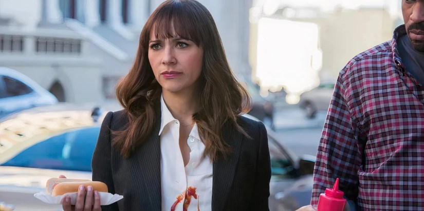 Rashida Jones as Angie Tribeca looking unimpressed with ketchup on her shirt and holding a hotdog in Angie Tribeca.