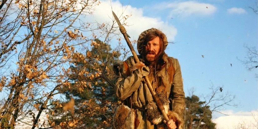 Man in the Wilderness movie 1971 - Richard Harris as Zachary Bass in rugged, tattered clothes with a make shift spear in woodland