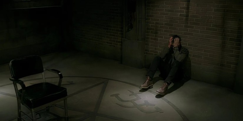 Jensen Ackles as Dean Winchester sat on the floor in defeat with his head in his hands in the Supernatural episode Despair.