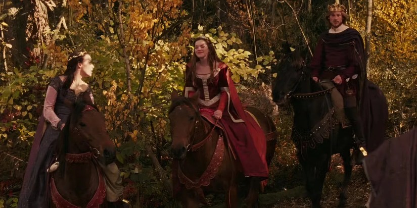 Adult Lucy, Susan, and Peter riding horses through a forest in The Lion, the Witch and the Wardrobe