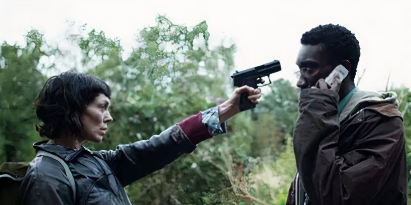 Fiona O&rsquo;Shaughnessy as Jessica Hyde pointing a gun at Nathan Stewart-Jarrett as Ian Johnson, while he talks on the phone, in Utopia.