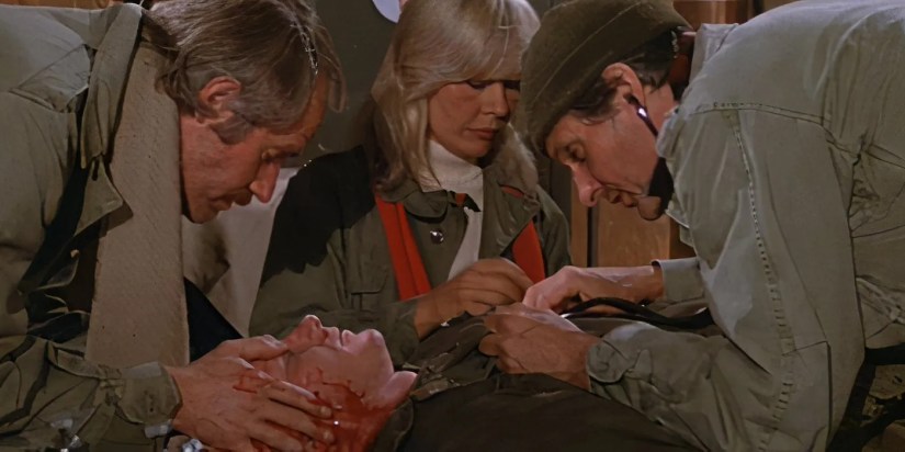 Hunnicutt, Margaret, and Hawkeye working on a bleeding soldier in the MASH episode &ldquo;Death Takes a Holiday.&quot;
