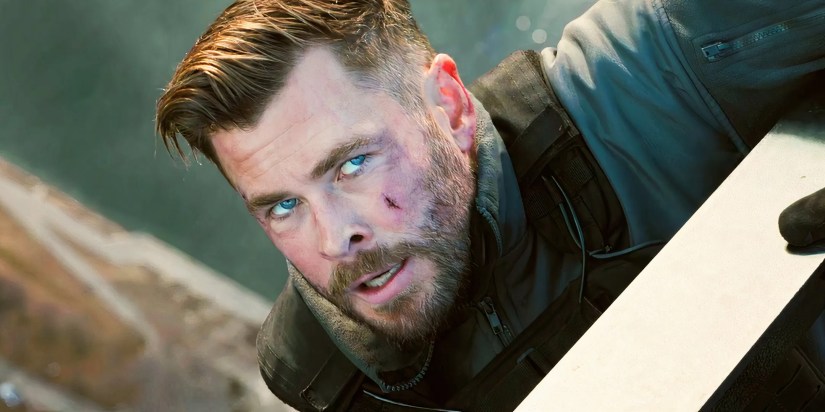 Chris Hemsworth holding onto the edge of a building as Tyler Rake in Extraction 2