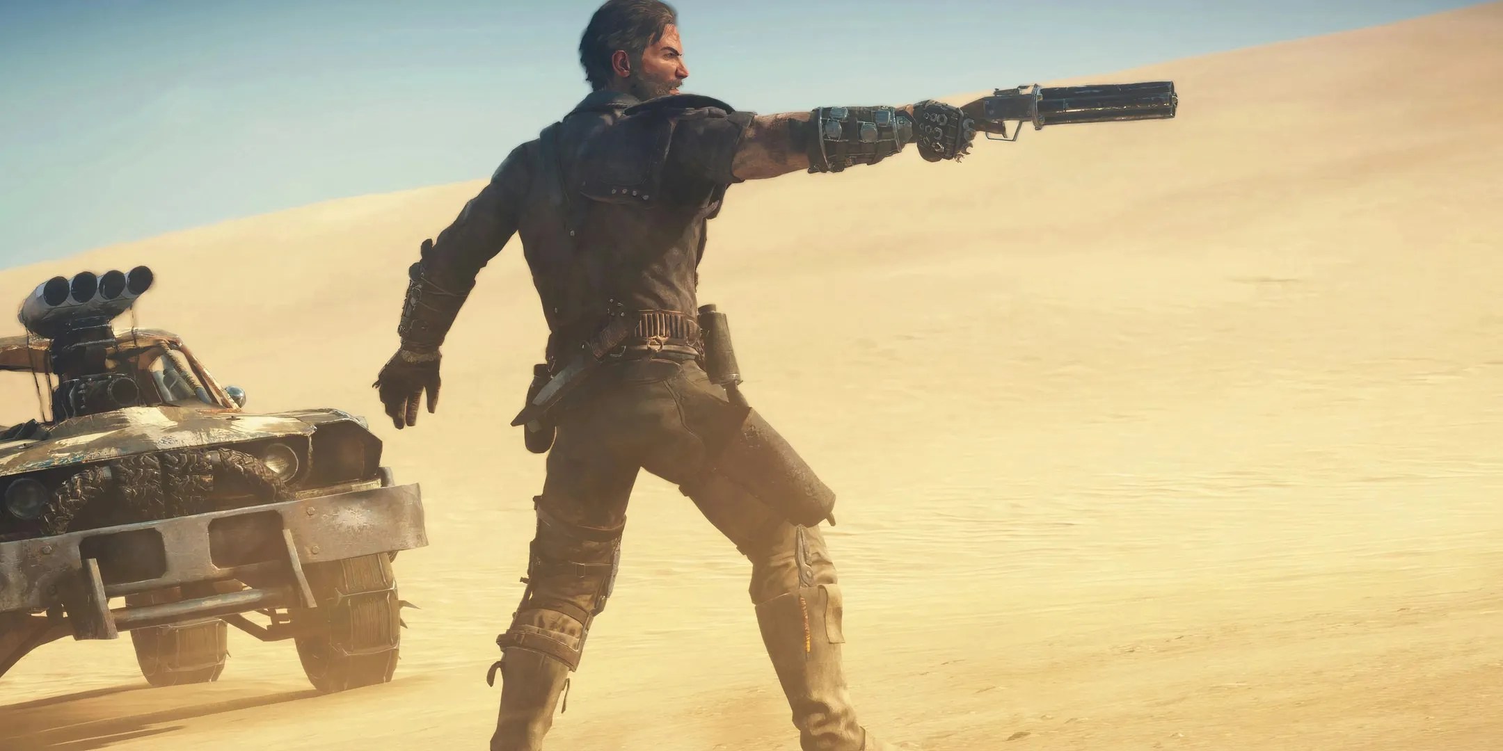 Main character Max Rockatansky points his gun at something in the desert in Mad Max