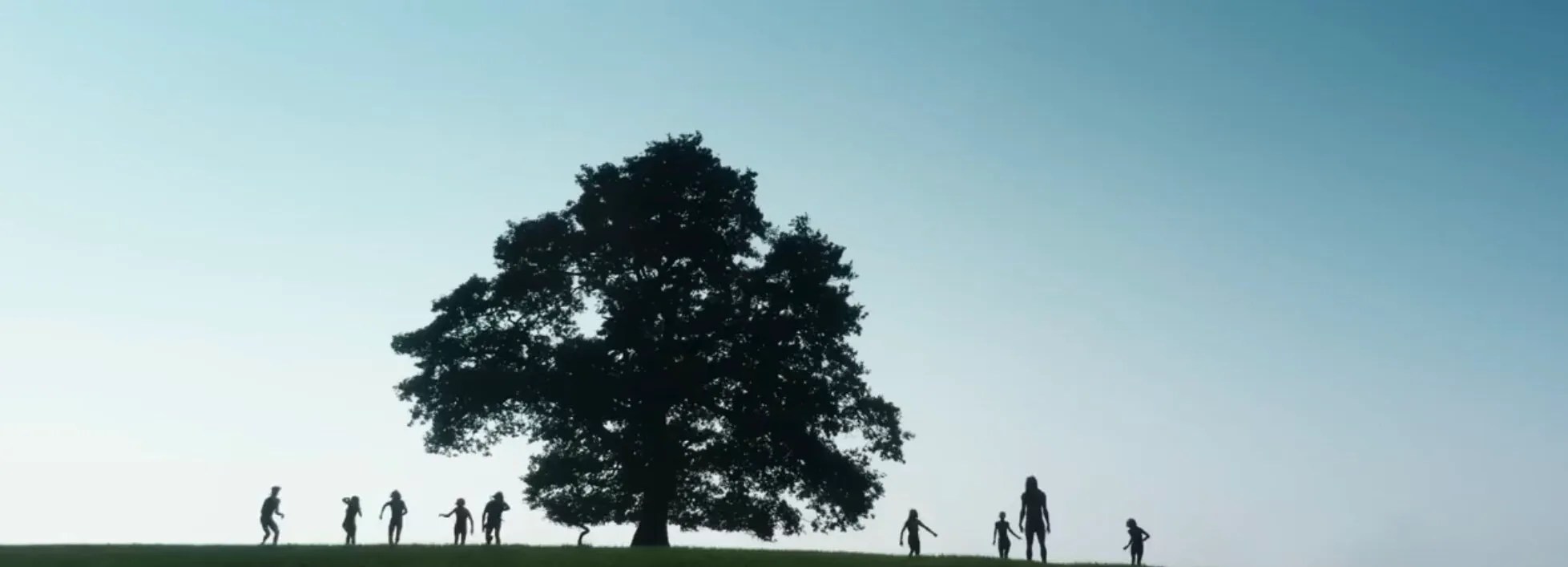 Infected stand atop a hill next to a tree in 28 Years Later.