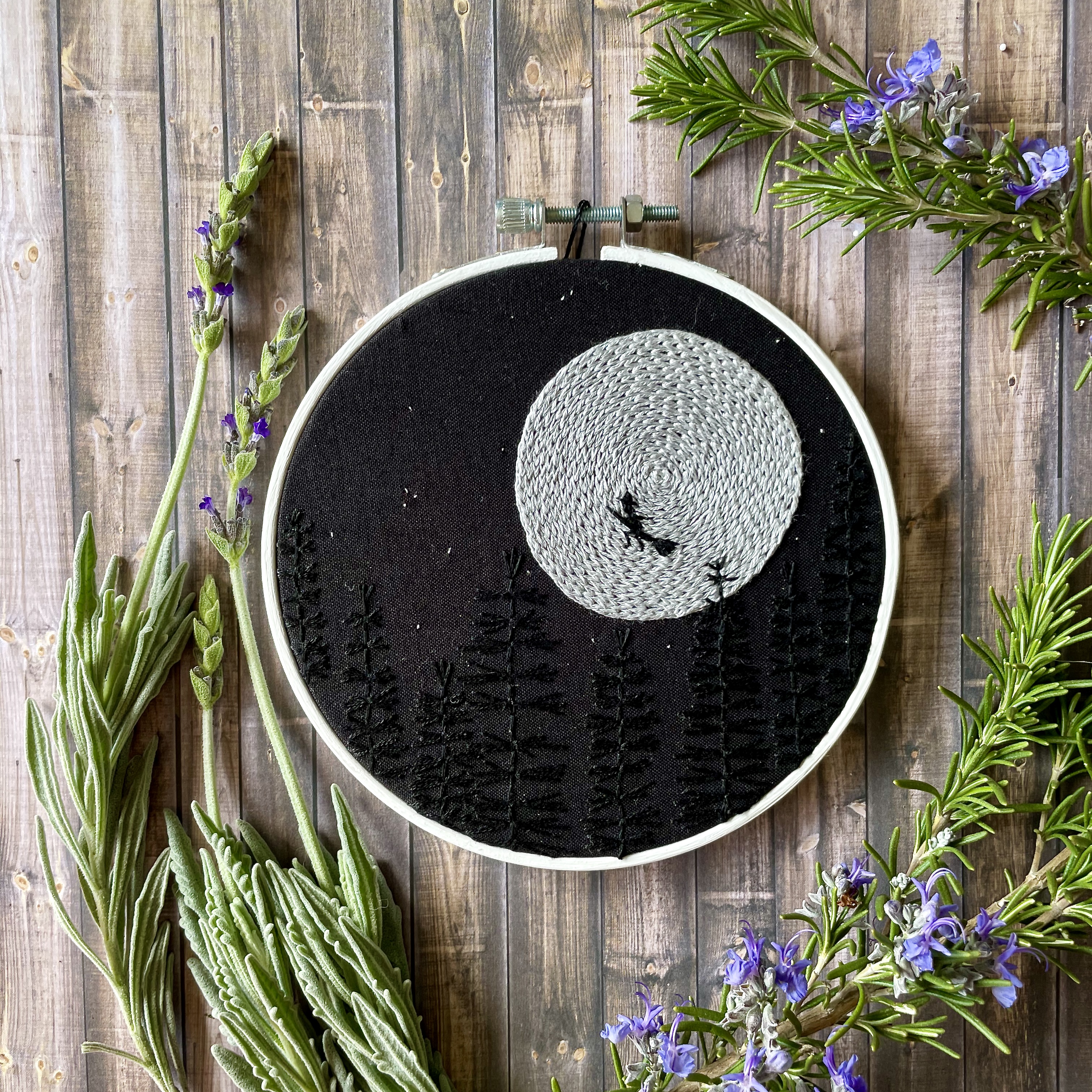 witch embroidery framed in a white bamboo hoop.
