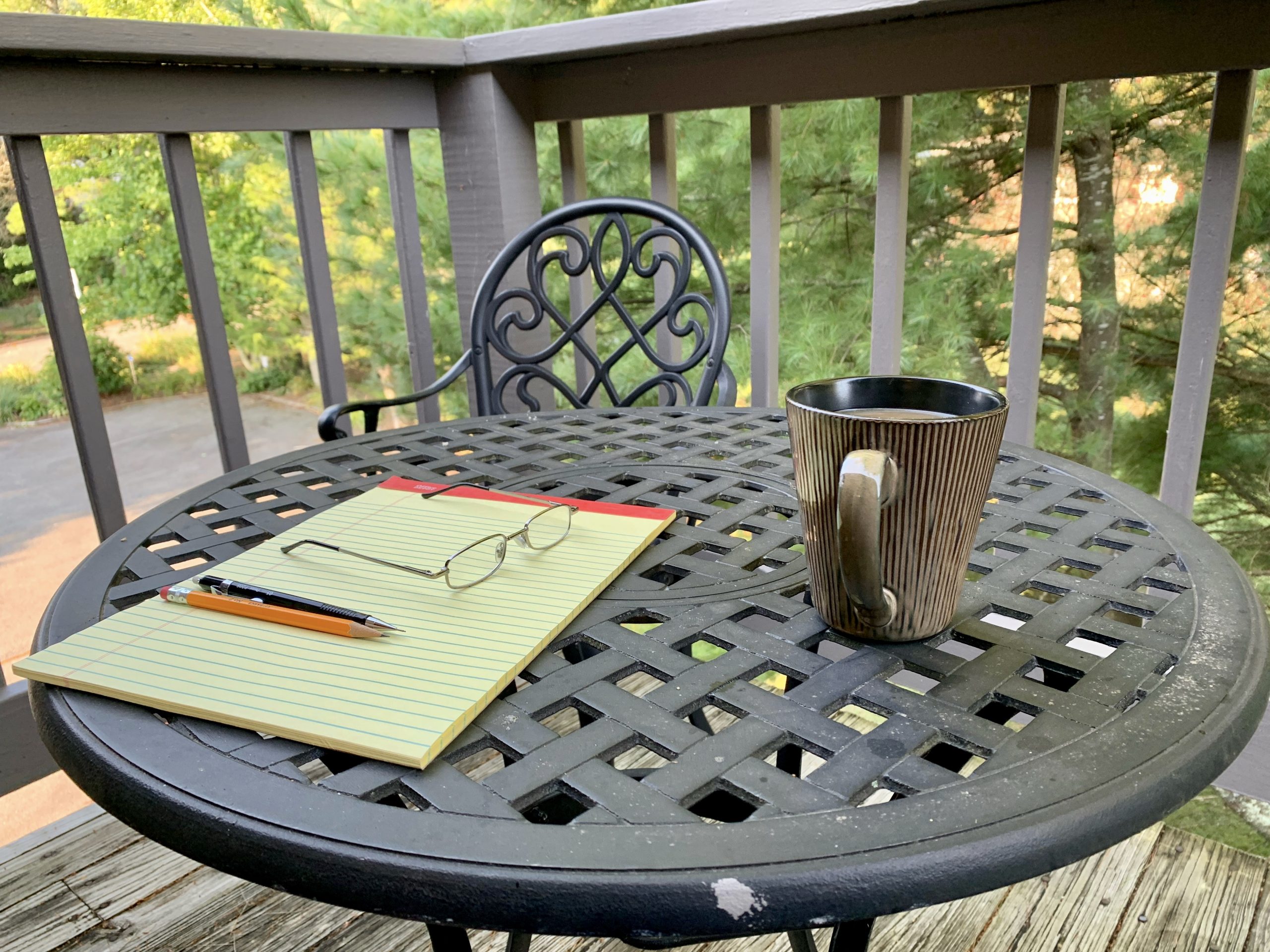 Paper, pen, and coffee mug sit on a table aon a patio in North Carolina