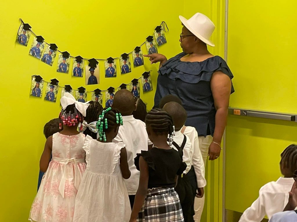 A staff member points out pictures of graduates hanging on the CHILD Center wall during Graduation 2022