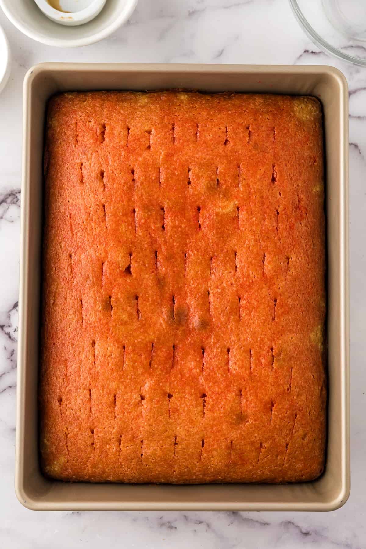 A square of orange cake in a baking pan, perfect for serving at parties.