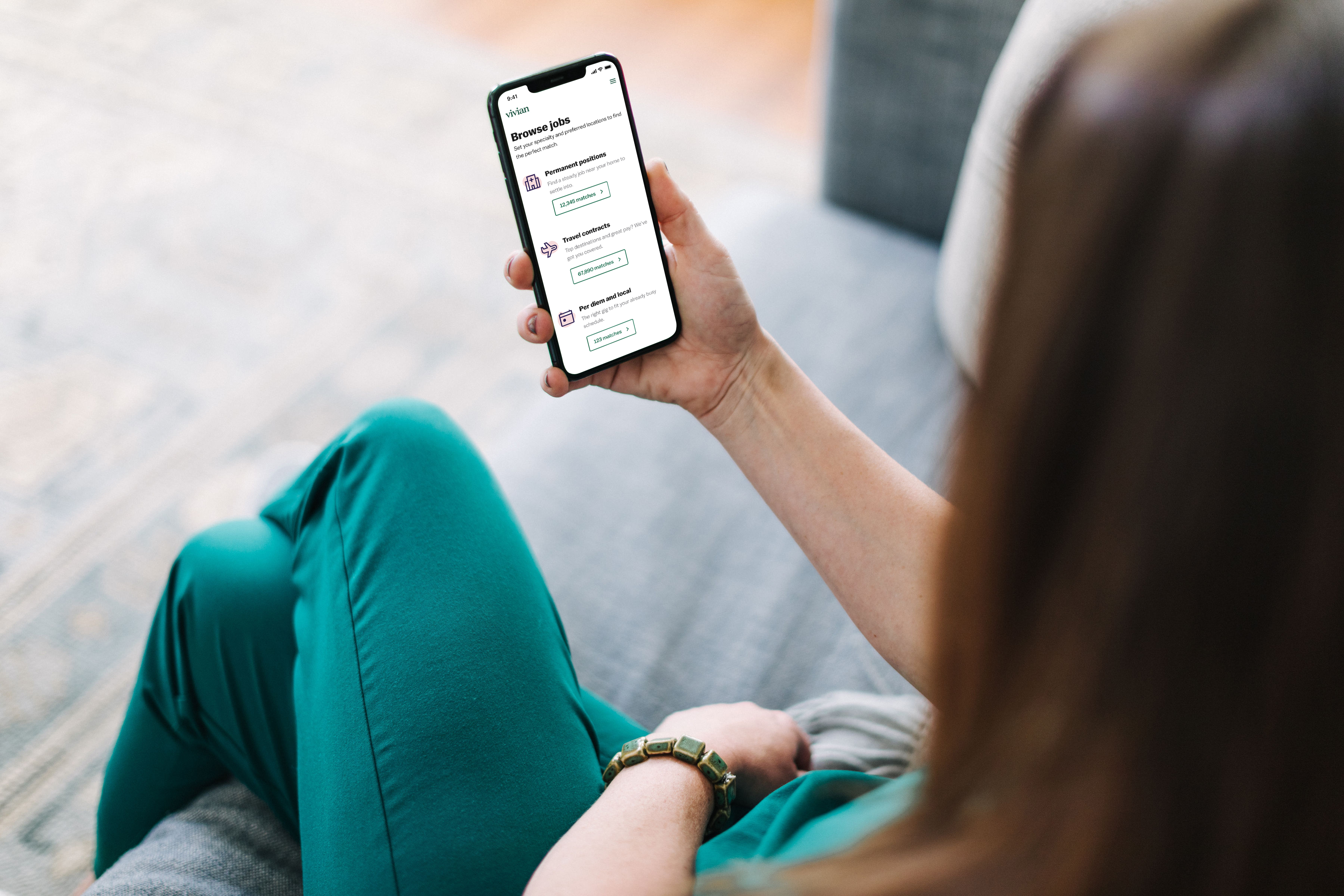 A photo of a person wearing healthcare scrubs holding a smartphone with