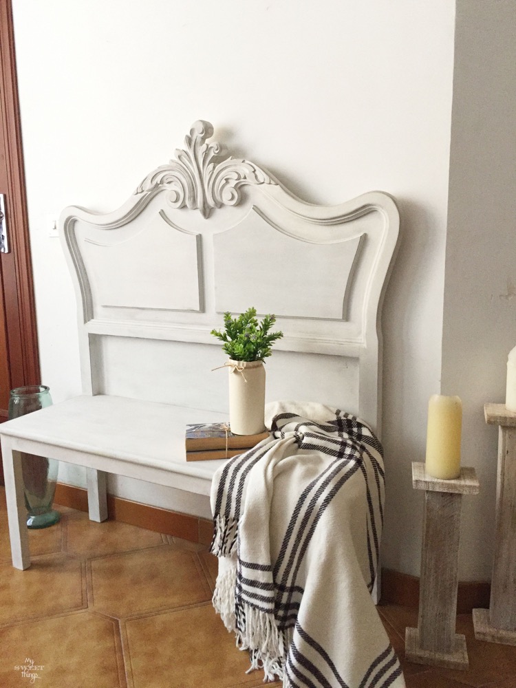 This re-purposed vintage headboard painted white is antique and compliments the tile floor.