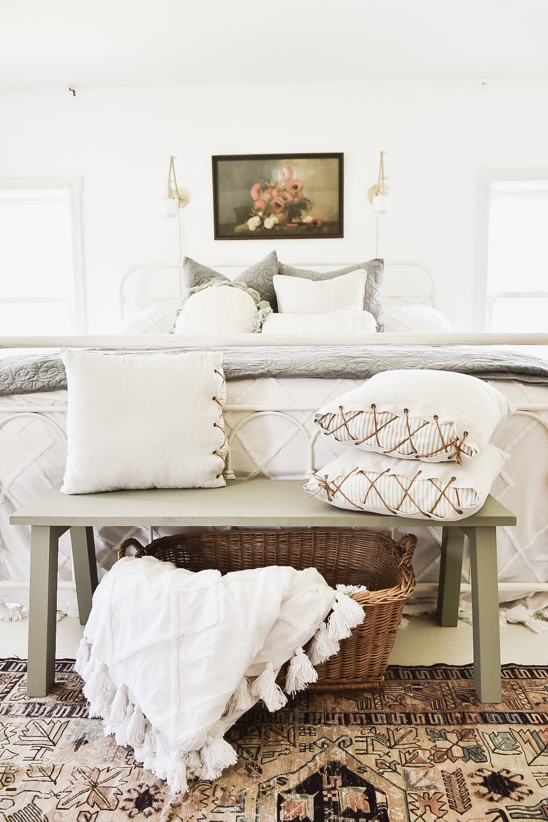 These unique throw pillows and patterned rug add to the white tones in this farmhouse bedroom.