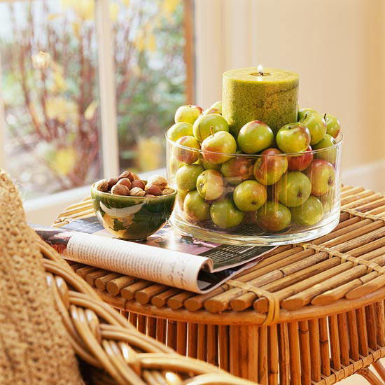 This DIY fall centerpiece made with several green apples and a large candle is festive.