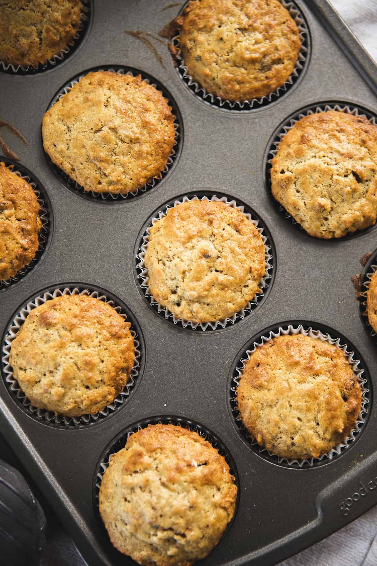 Golden bran muffins sit in a muffin tin, fresh out of the oven.