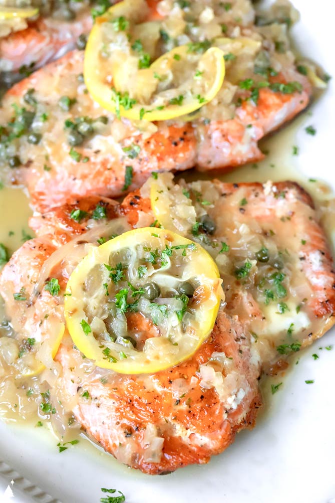 Tender, perfectly cooked fish, and a luxurious sauce spiked with capers, this salmon piccata makes an easy dinner feel extra elegant. #salmonpiccata #lowcarbsalmonpiccata closer view of salmon piccata healthy with garnish