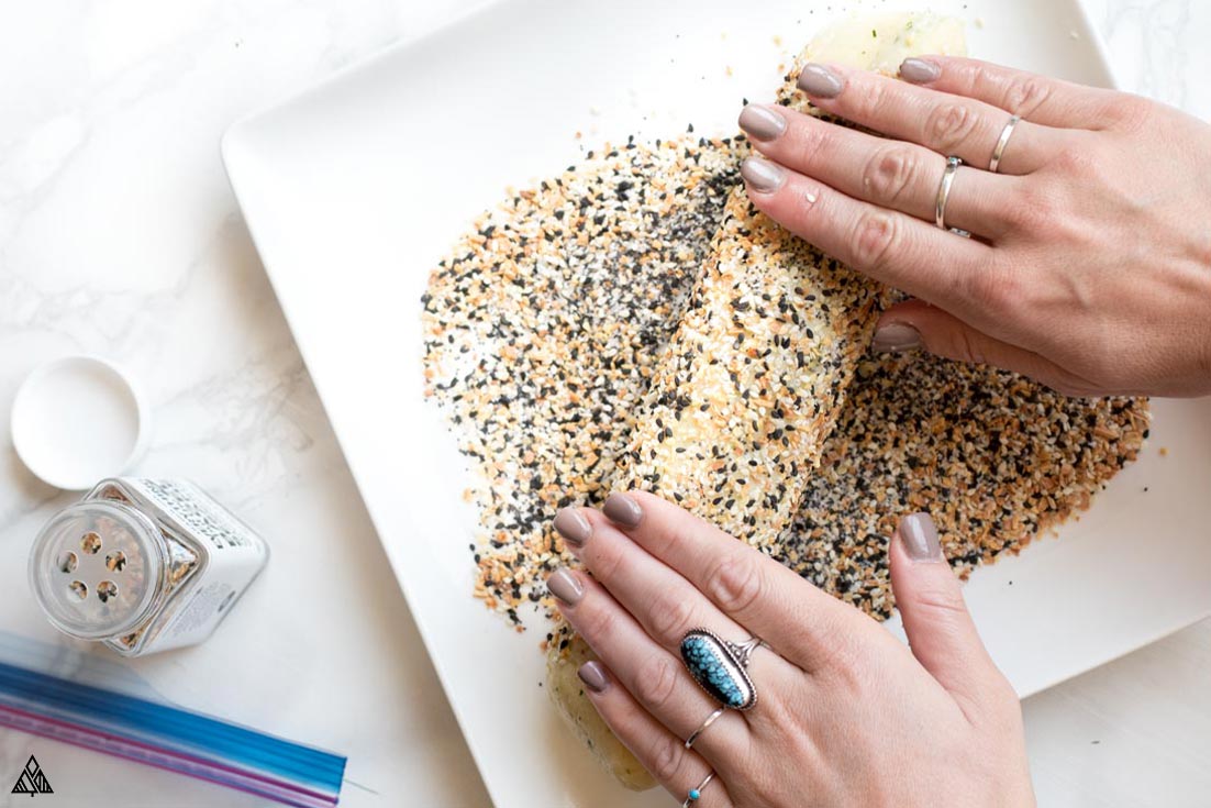 This Fathead crackers recipe is cheesy, crunchy and the most addicting healthy snack ever! Bake some today today and see yourself just how easy and delicious they are! #fatheadcrackers #lowcarbfatheadcrackers Rolling the dough into a plate full of sesame seeds