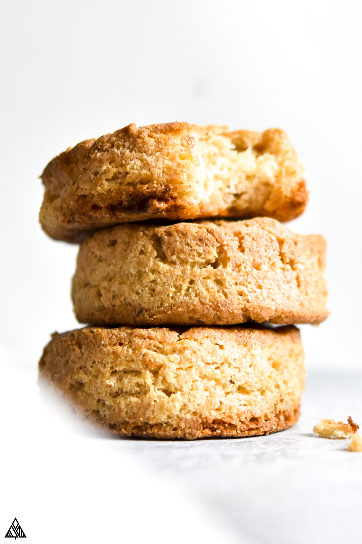 This homemade, buttery keto biscuits recipe is one to write home about. In fact, invite the whole family over to try them. #lowcarbbiscuits #ketobiscuits keto biscuit stacked and a bite taken out of it