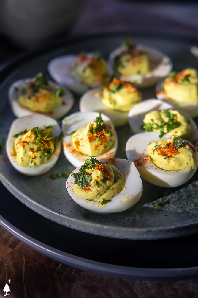 These keto avocado deviled eggs are light and delicious, incredibly smooth and rich with a zing of lime and jalapeño to keep things light. #ketoavocadodeviledeggs #lowcarbavocadodeviledeggs closer view of avocado deviled eggs without mayo on a plate