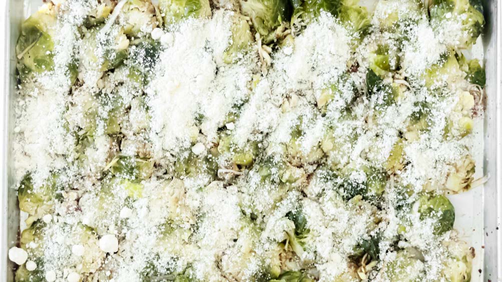 *NEW* Crispy baked parmesan cover these smashed brussels sprouts, for a tasty side dish that'll forever change the way you feel about this veggie! #smashedbrusselssprouts #lowcarbsmashedbrusselssprouts top view of smashed brussels sprouts with parmesan