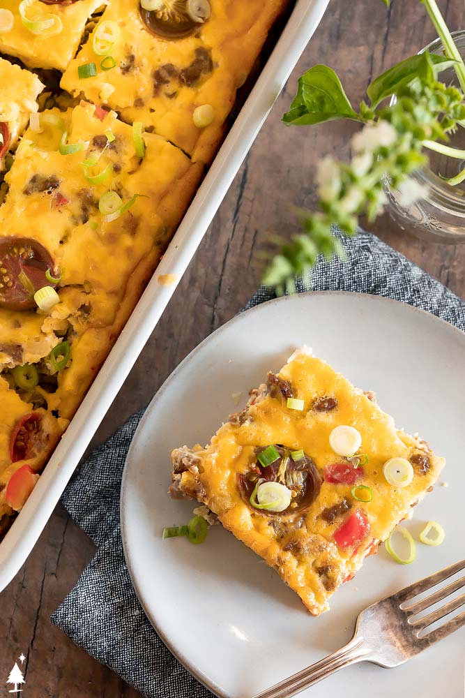 Zesty sausage, melty cheese, and sauteed veggies unite for a keto breakfast casserole that’s best described as convenience meets hearty! #ketobreakfastcasserole #lowcarbbreakfastcasserole top view of sliced italian sausage casserole in a plate