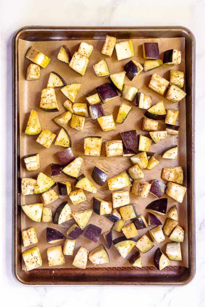 Flavorful, satisfying plus easy to make, this roasted eggplant is a perfect example of how tender and delicious roasted veggies can be! #roastedeggplant #lowcarbroastedeggplant top view of roasted eggplant slices on a baking sheet