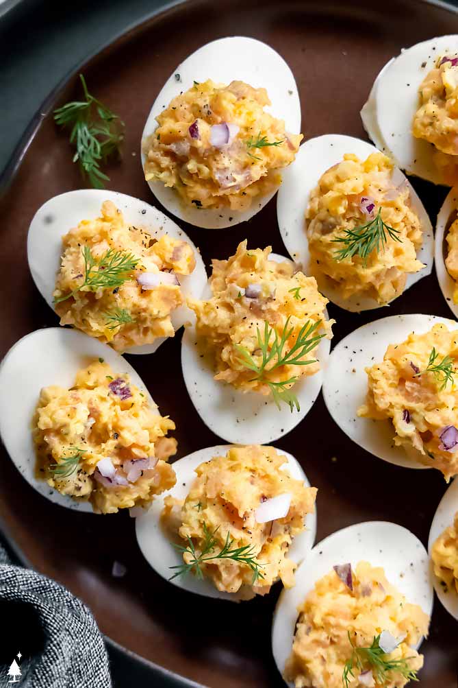 *NEW* Creamy with a bit of tang, these smoked salmon deviled eggs are the most glamorous way to eat eggs--perfect for appetizers AND snacks! #smokedsalmondeviledeggs #lowcarbsmokedsalmondeviledeggs top view of smoked salmon hard boiled eggs on a plate