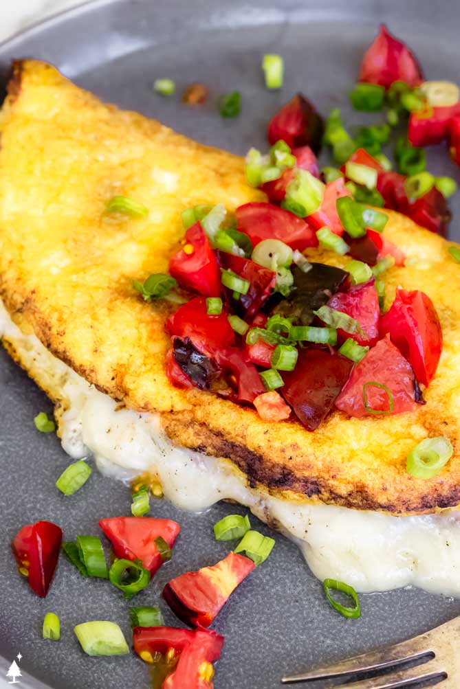 egg soufflé on a plate with tomatoes and green onions