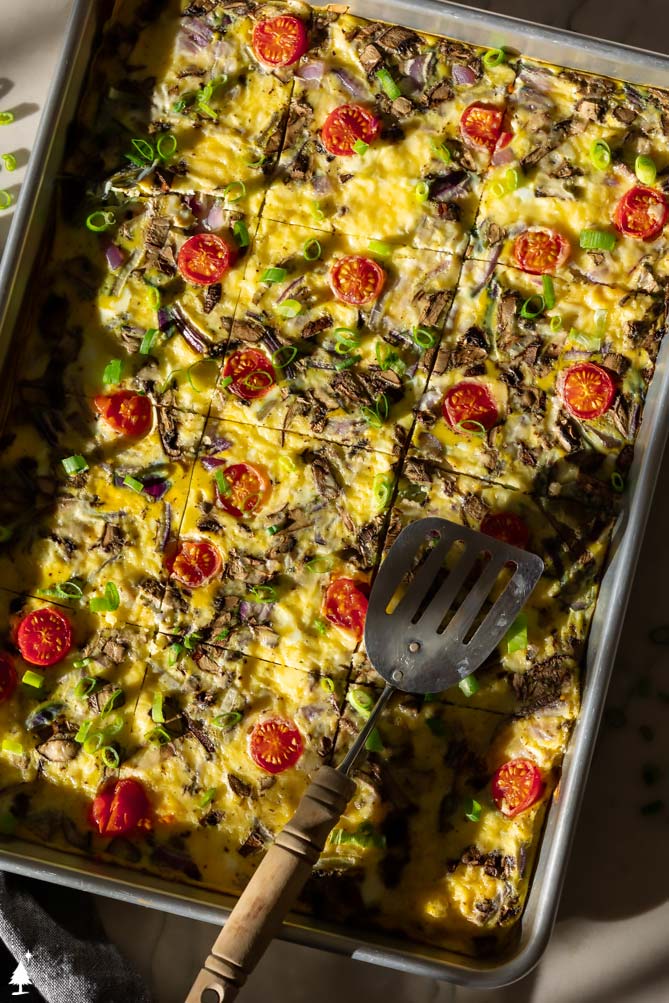 egg patty with tomatoes and red onions and a spatula
