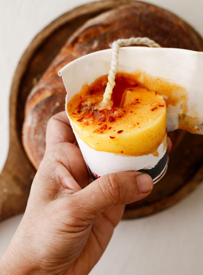a hand ripping a paper cup away from a homemade butter candle