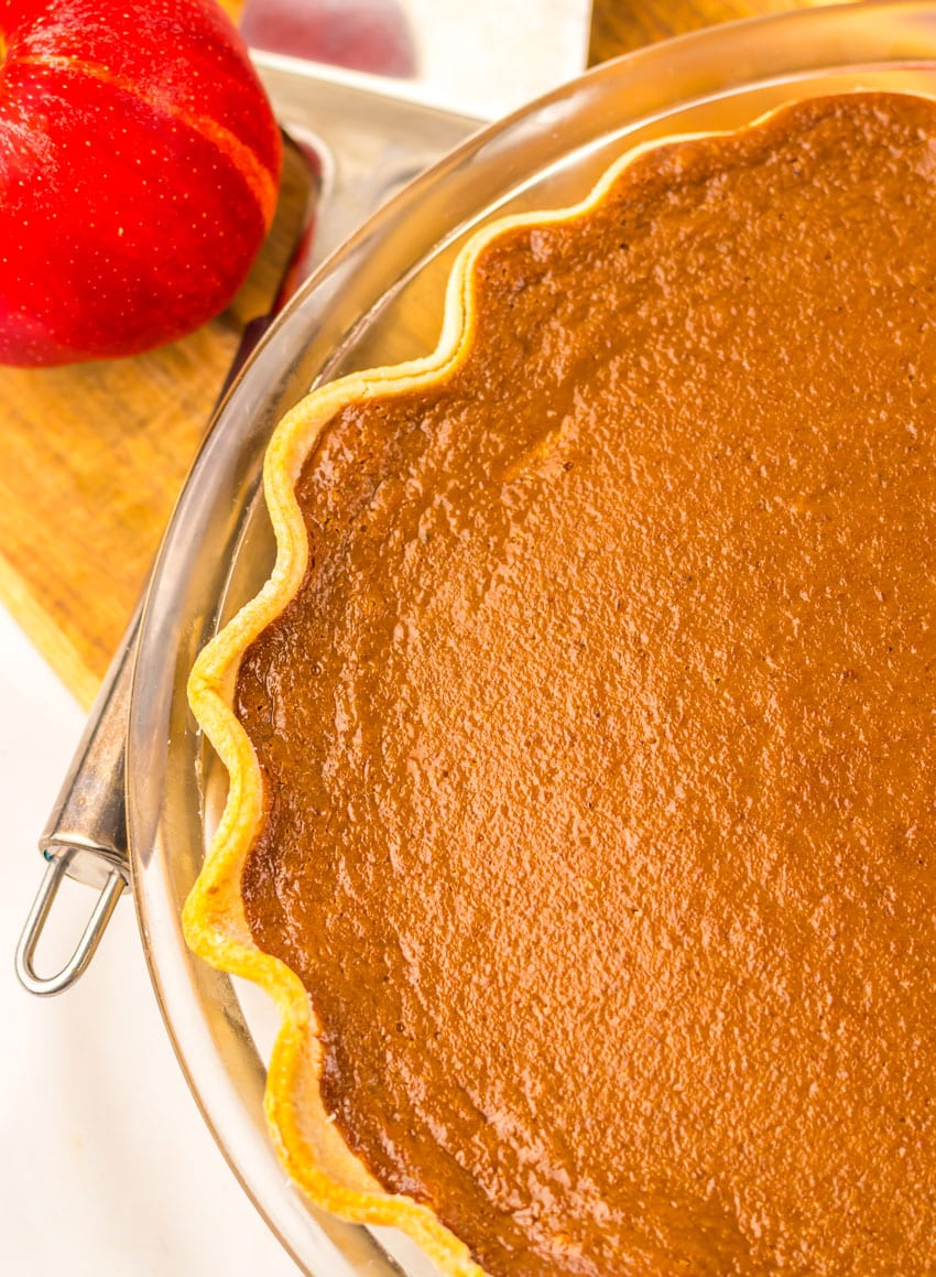 a close up image of a baked apple butter pie cooling on a wooden cutting board