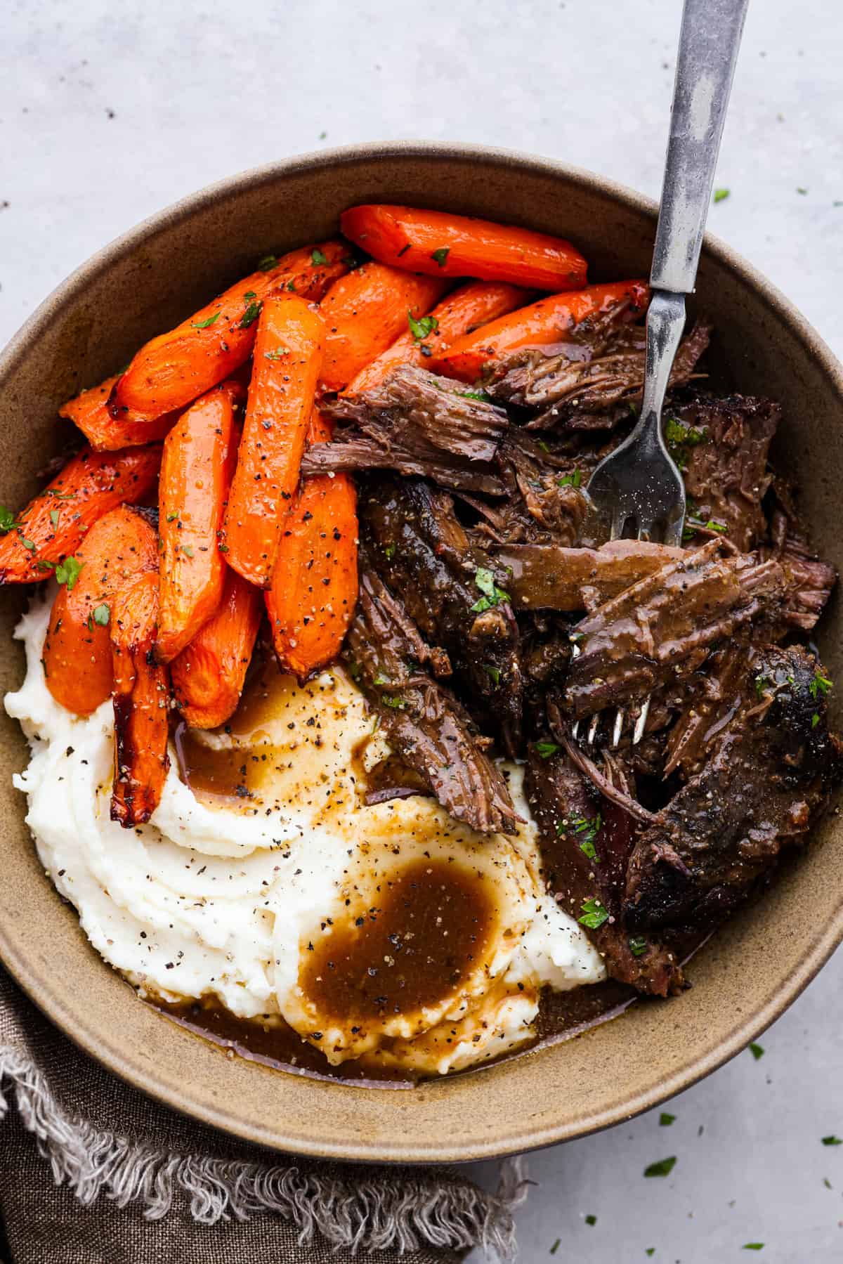 This 3 packet roast is my go-to for an easy but delicious Sunday dinner. Add brown gravy, Italian dressing, and ranch dressing powders to a slow cooker with your beef and then let it work its magic! It creates an ultra-tender, flavorful roast you’ll love coming home to at the end of the day. Shredded pot roast served with carrots and mashed potatoes.