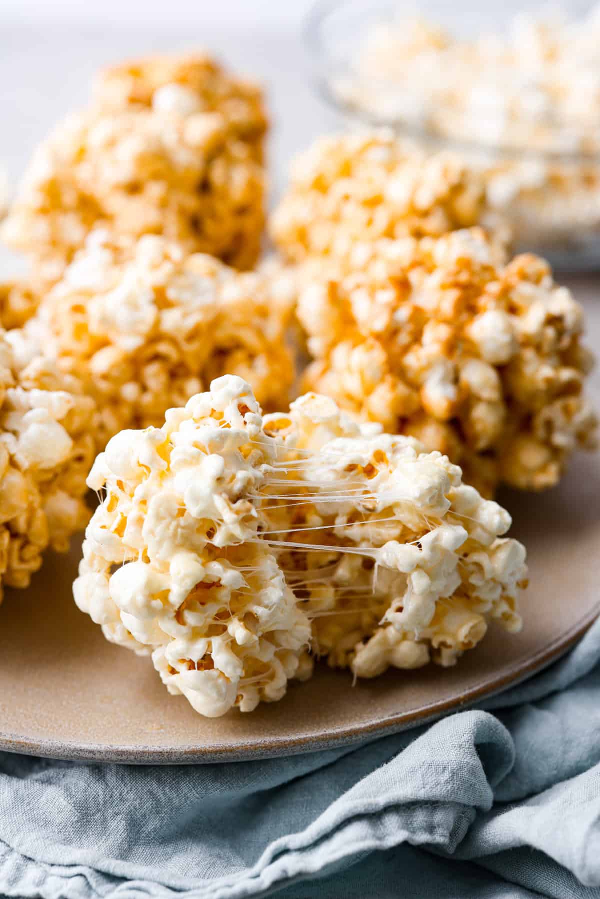 These popcorn balls are a tasty snack that will win the hearts of kids and adults alike! This recipe has 3 different flavors, marshmallow, peanut butter, and caramel, so there's something for everyone! You're going to love each soft and buttery bite. One ball of popcorn torn in half.