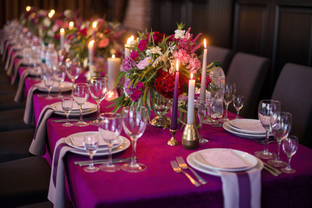 Elegant dark pink wedding banquet table with glasses, dishes and