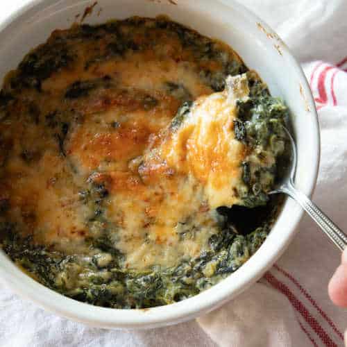 A baking dish of creamed spinach topped with cheese.