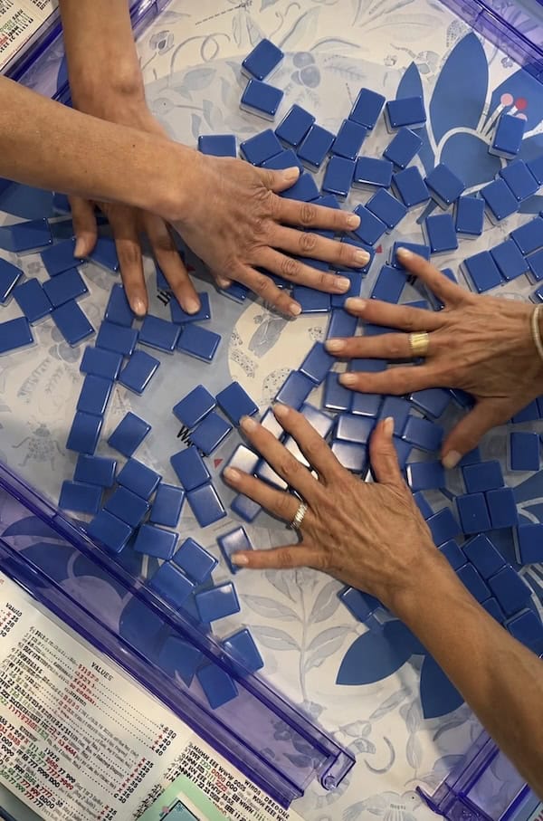 four hands mixing up mahjong tiles.