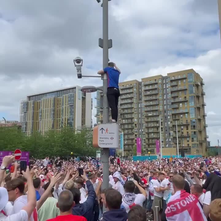 Fan Climbs Up a Light Post As People Throw Beer Cans At Each Other
