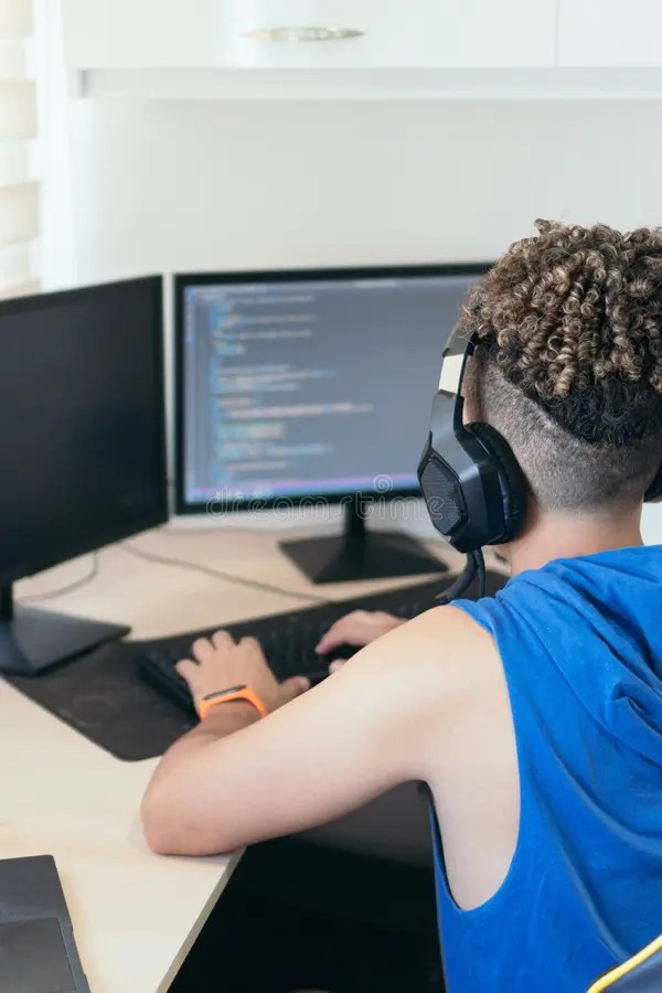 Computer Programmer Sitting at Desk and Typing on Computer Keyboard