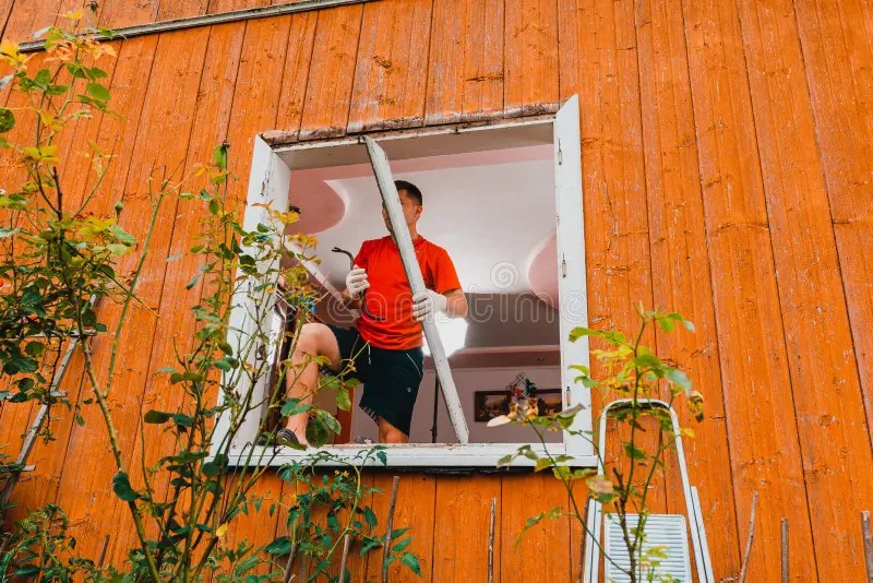 Worker Removing Old Window in Flat. Replacement of Window Frames. Stock