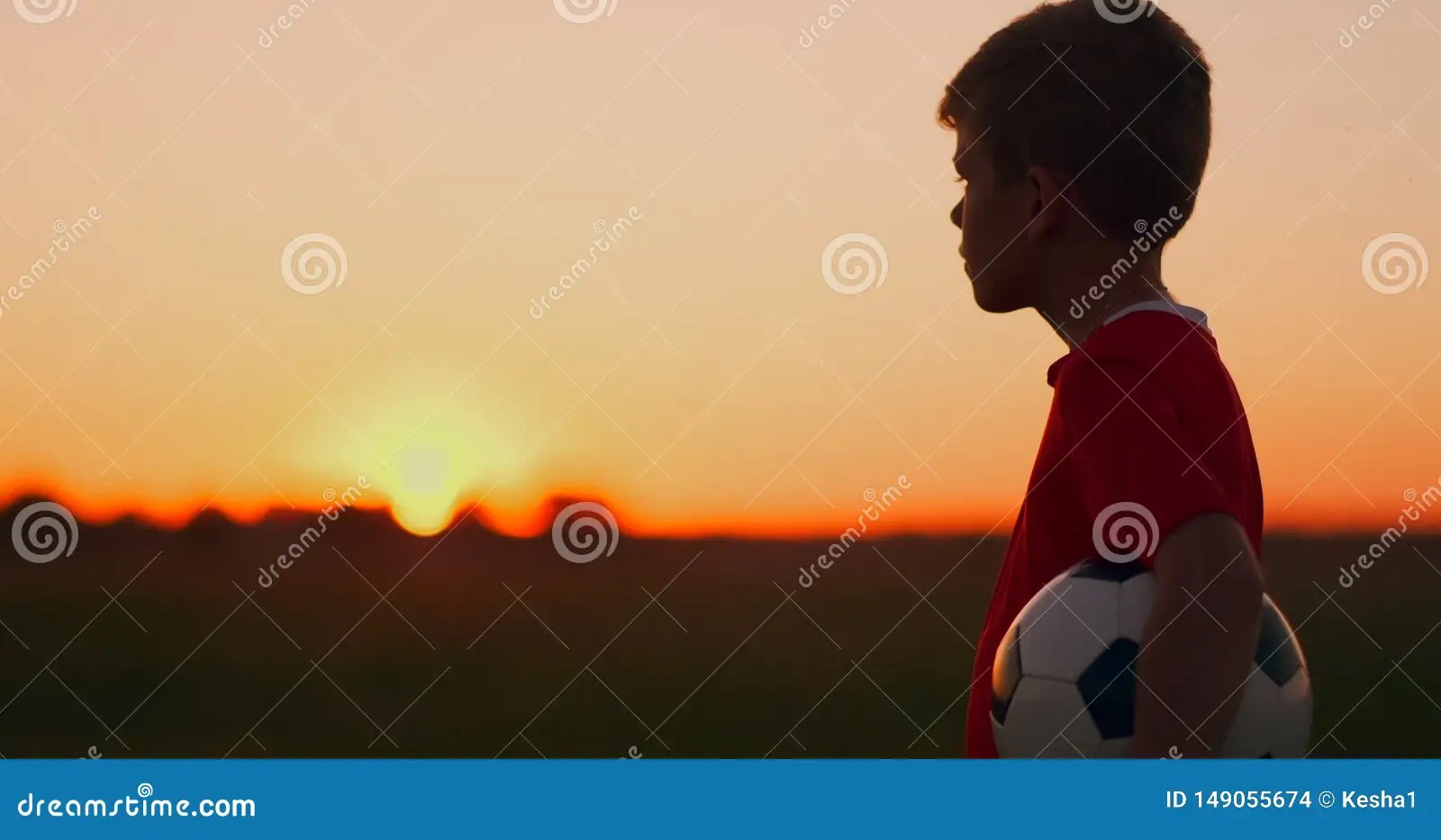 Young Football Player Goes with the Ball on the Field Dreaming of a