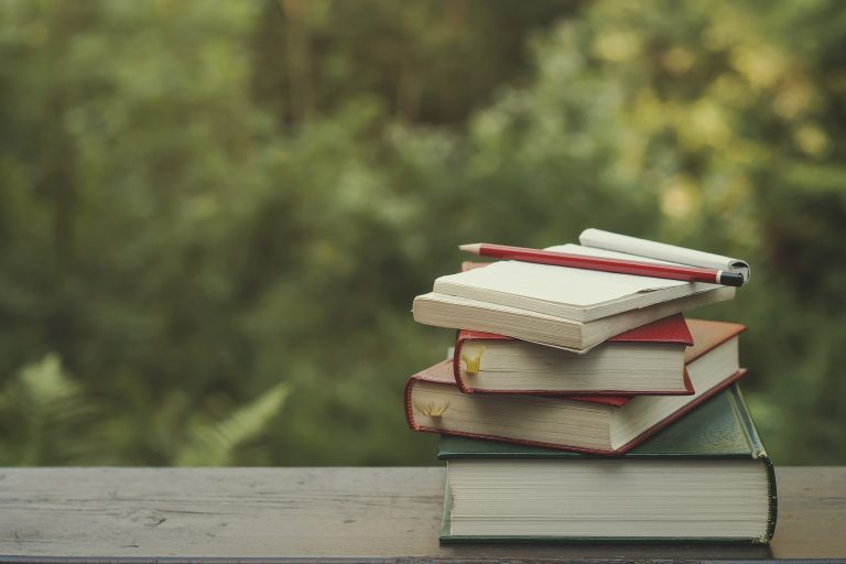 pile of books on a garden wooden table, green nature