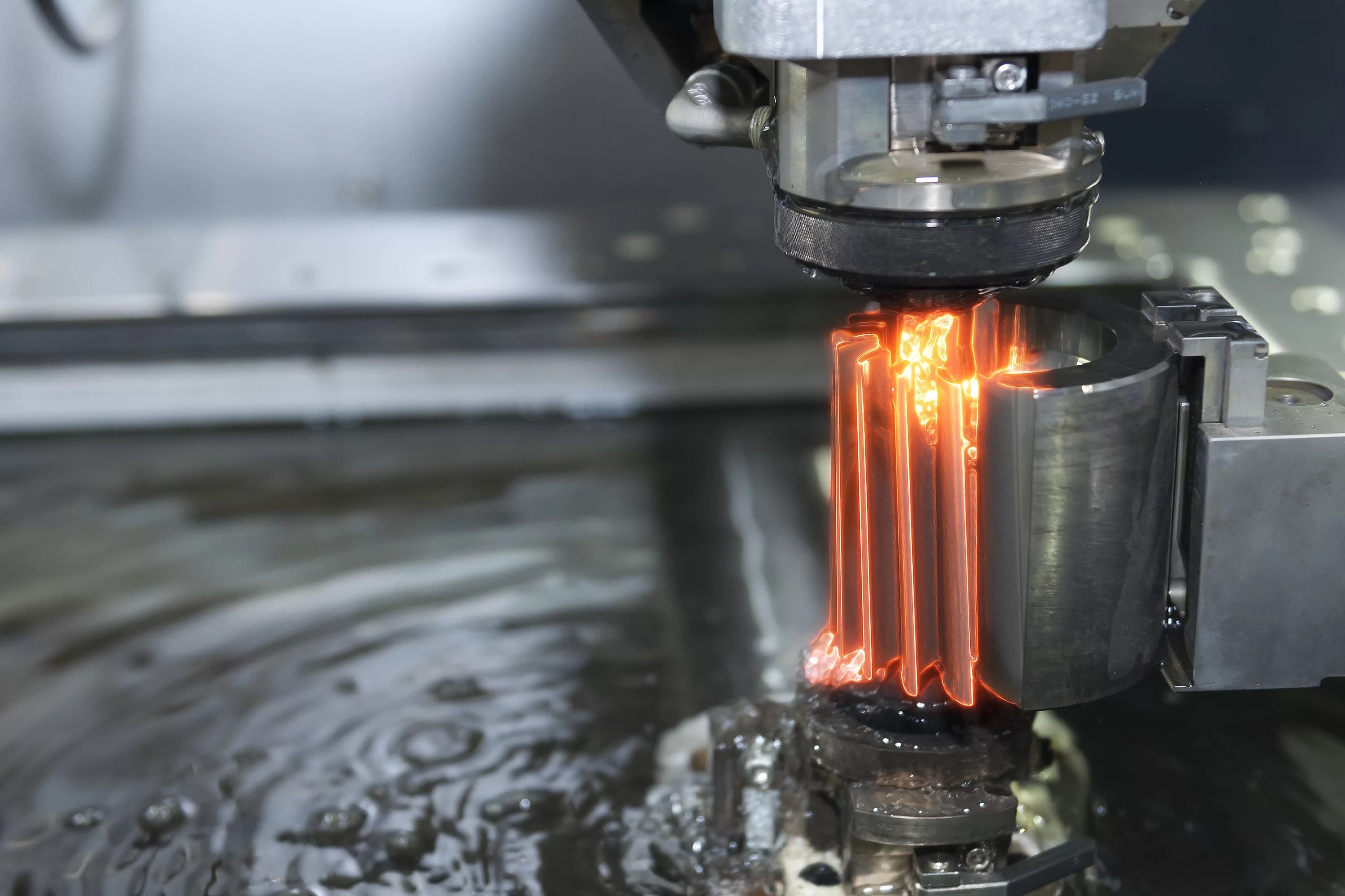 EDM CNC machine while cutting the sample part with glowing edge