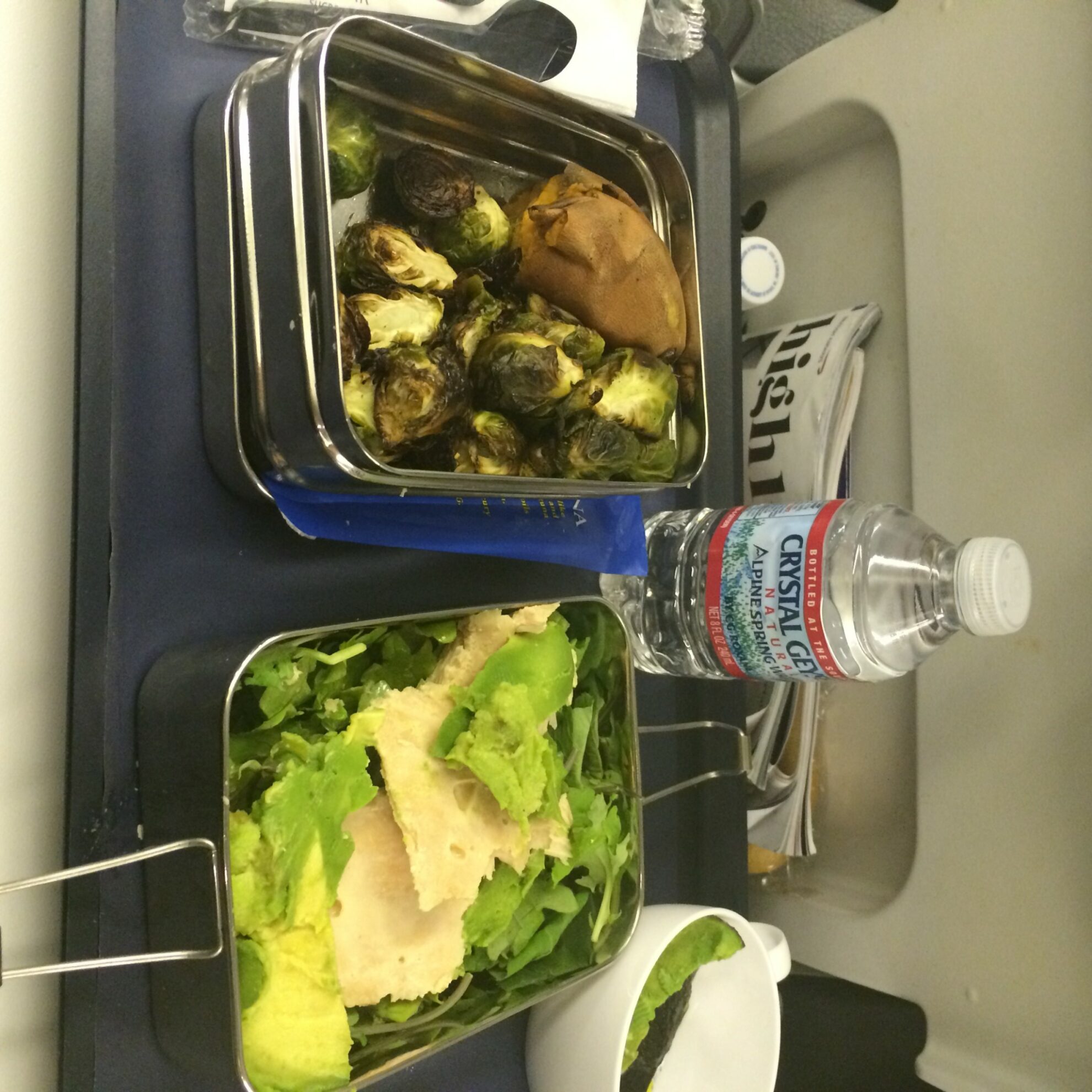 A plane tray table with containers of food on it.