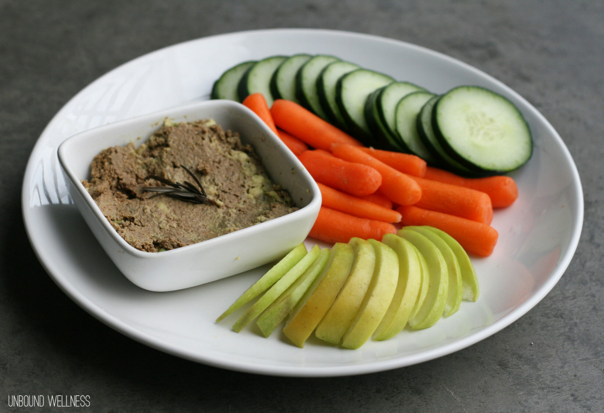 A plate with raw vegetables and dip on it.